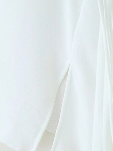 Gros plan sur la texture du tissu blanc et la fente d'une robe longue romantique à manches