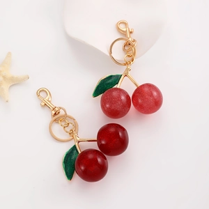 Detailed view of dual cherry keychains with resin glitter pendants and golden hardware