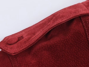 Close-up of shoulder strap and button stitching detail on red faux suede jacket