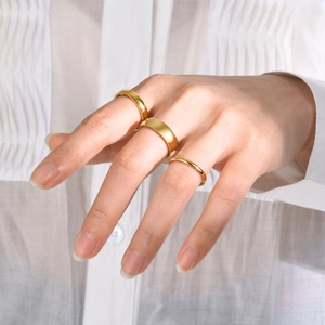 Three-piece gold titanium steel rings in various widths worn by model on white fabric