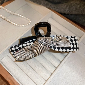 Macro detail of checkered hair claw clip with rhinestones and elegant bow design