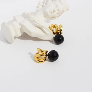 Vintage gold spiral earrings with black onyx pendants shown against a white marble bust
