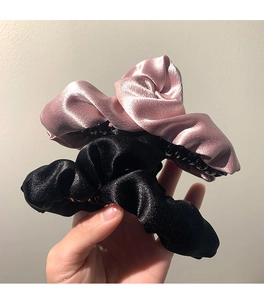 Dettaglio delle pinze per capelli in raso rosa e nero con elegante trama pieghettata
