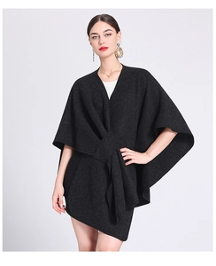 Close-up of black oversized knit poncho with front-tie knot and irregular hemline