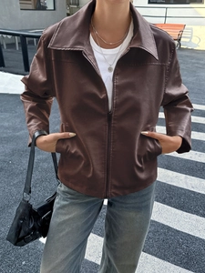 Dettaglio di una giacca in finta pelle marrone con revers e chiusura lampo su un modello