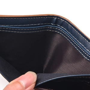 Detail of dark blue bifold wallet showing dual bill compartments and contrast stitching