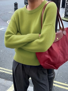 Detail shot of green crewneck knit sweater with ribbed cuffs and textured soft material