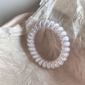 Detail of spiral telephone wire hair tie with colorful polka dots on white base