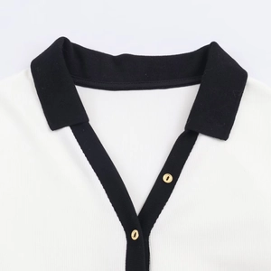 Detail of contrast lapel collar with gold buttons on black and white ribbed knit top