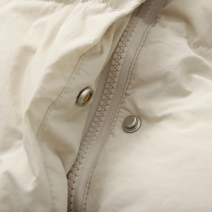 Close-up of cream beige bomber jacket featuring resin zipper and metal snap button details