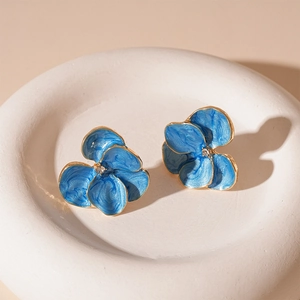 Detailed macro shot of blue marble enamel flower earrings with gold plating and zircon center