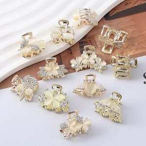 Close-up of mini gold hair claws with opal flowers, hearts, and sparkling rhinestones