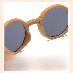 Detail view of round children sunglasses featuring matte brown frame and integrated nose pads