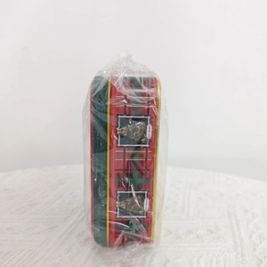 Close-up of red and green plaid Christmas tin boxes in sealed transparent packaging