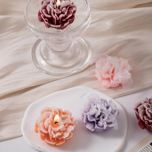 Macro shot of carnation flower scented candles in pink and purple on a white ceramic plate