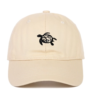 Close-up of embroidered black turtle design on a beige cotton twill baseball cap