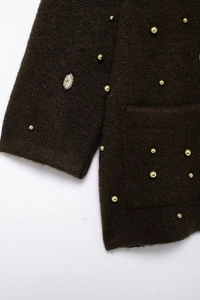 Detailed macro view of dark brown knit cardigan with gold beads and oval rhinestone accents