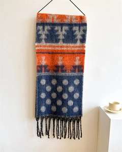 Detail of cashmere-like scarf showing deep blue and orange polka dot patterns with fringe