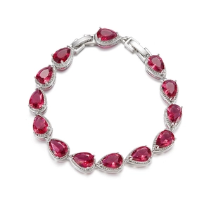 Detailed macro view of pear-shaped red zircon gemstones set in a silver bracelet band