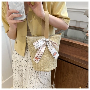 Détail d'un sac seau en paille avec poignée PU kaki, foulard soie et chaîne métal