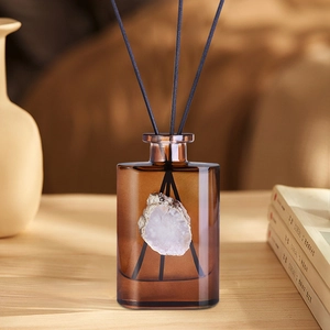 Amber glass aromatherapy diffuser with white agate stone and black reeds in cozy home setting