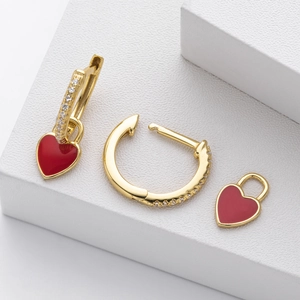 Macro shot of gold hoop earrings with red enamel hearts and white zircon stones