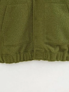 Close-up of olive green wool bomber jacket showing fabric texture and utility pockets
