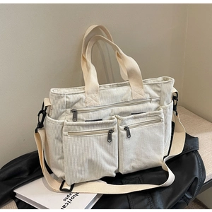 Detail of off-white corduroy shoulder bag with multi-pocket design and canvas strap