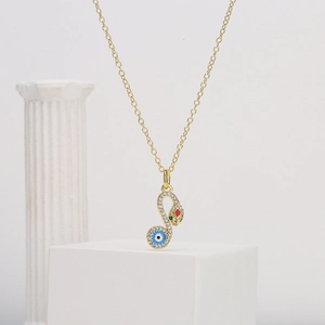 Gold-plated snake necklace with zircon stones and blue evil eye charm on white pedestal
