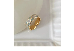 Close-up of gold butterfly ring featuring green enamel and quilted pattern on ceramic
