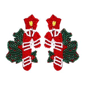 Detail of handmade beaded Christmas earrings with red bow and holly berry design