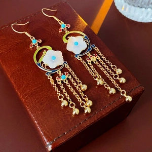 Detailed macro view of vintage gold-plated flower earrings with enamel clouds and long tassels