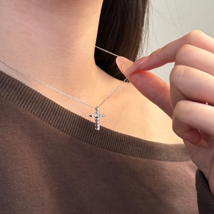 Close-up of S925 sterling silver cross necklace with inlaid stones on female neck