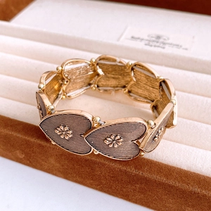 Macro shot of vintage gold heart-shaped elastic bracelet with floral relief detail