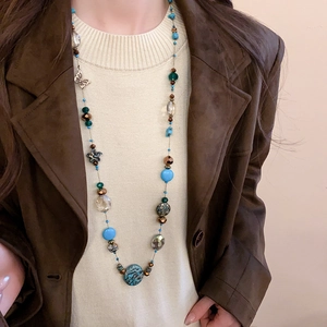 Close-up of bohemian layered beaded necklace with blue stones and butterfly charm on model