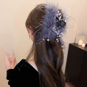 Detail of grey feather hair claw clip with glass beads worn on hair in cozy setting