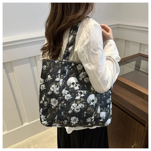 Close-up of the black tote bag featuring skull and floral prints on fabric material