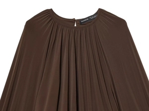 Close-up of brown pleated fabric texture with lantern sleeves and detailed collar label