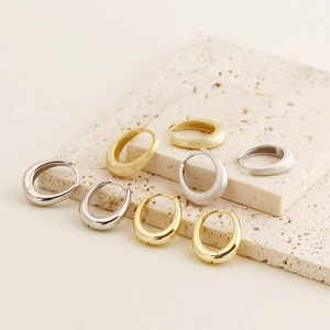 Detail of silver and gold huggie hoop earrings with polished and brushed finishes