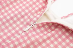 Close-up of pink and white gingham fabric texture with a hidden zipper detail