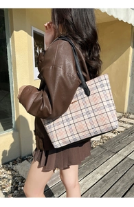 Close-up of classic check pattern tote bag with black leather handles on a model