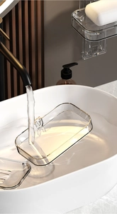 Detail of detachable transparent soap dish being rinsed under water for easy cleaning