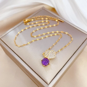 Luxury gold butterfly necklace with purple gemstone on a beige gift box display