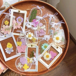 Transparent mason bottle dried flower bookmarks with colorful pressed plants and white ribbons
