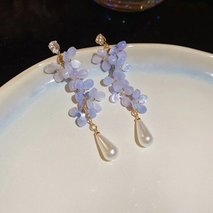 Macro detail of long tassel earrings with purple resin petals and white pearl drops