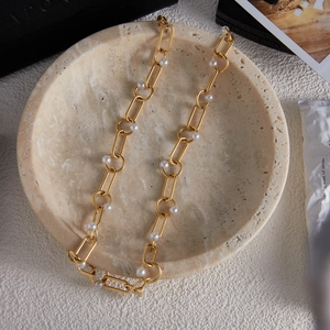 Close-up of gold titanium steel chain necklace with pearls on a stone tray