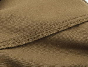 Macro shot of durable tan twill fabric with reinforced triple stitching on cargo skirt