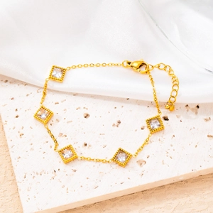 Detail of 18K gold plated clover bracelet with square zircon inlays on textured stone