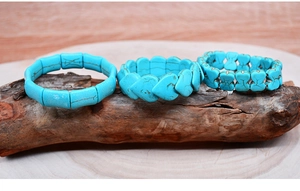 Detail of turquoise bead bracelets with heart and bow charms on natural wood surface