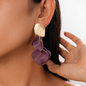 Close-up of model wearing gold metal earrings with matte purple flower petal pendants